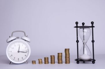 stacks of money and hourglass and clock on a white background