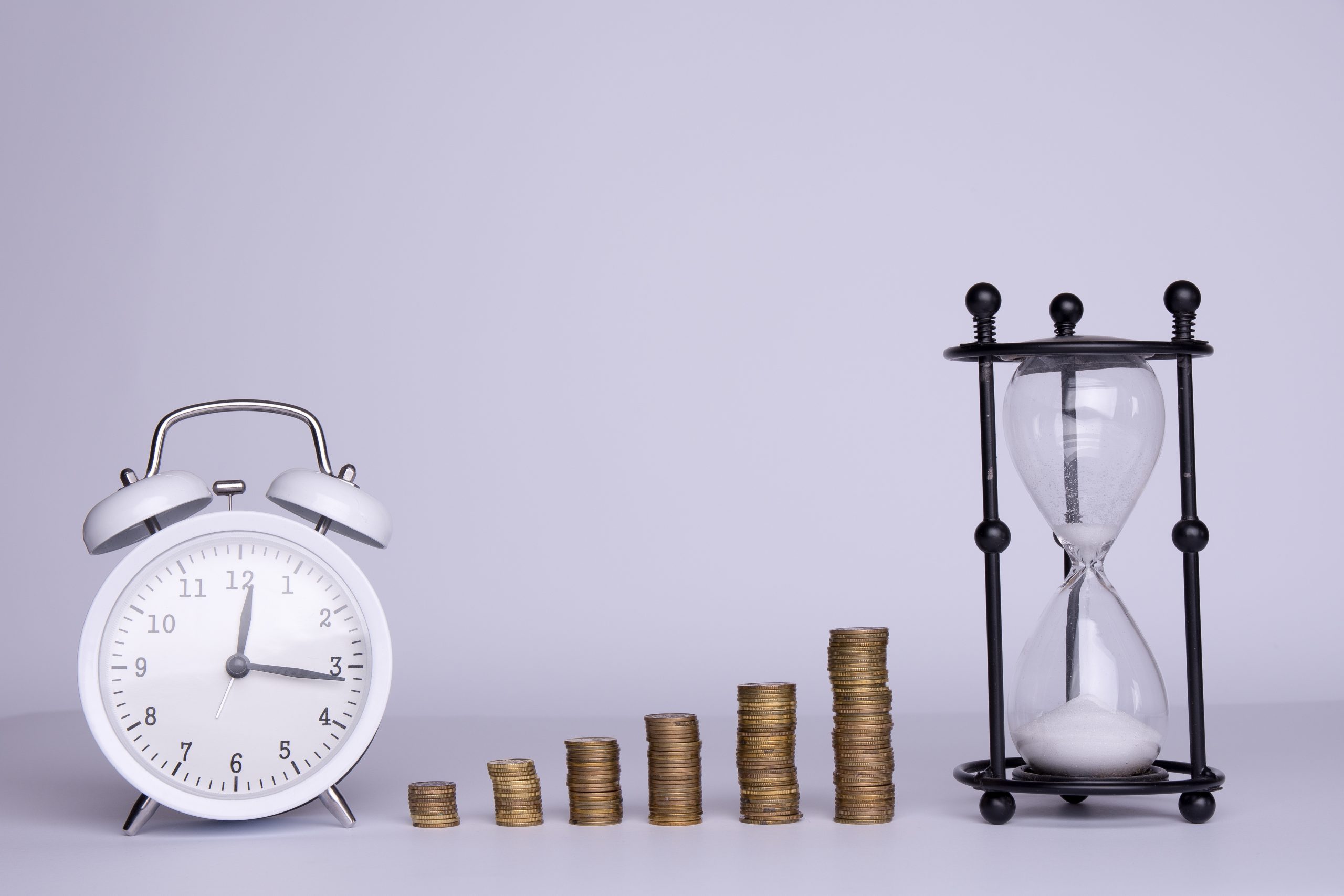 stacks of money and hourglass and clock on a white background stacks of money and hourglass and clock on a white background