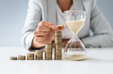Businesswoman With Hourglass And Stack Of Coins