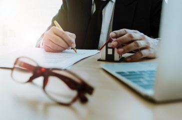 Young business signing a contract for house sell or rental with home model - Real Estate Concept
