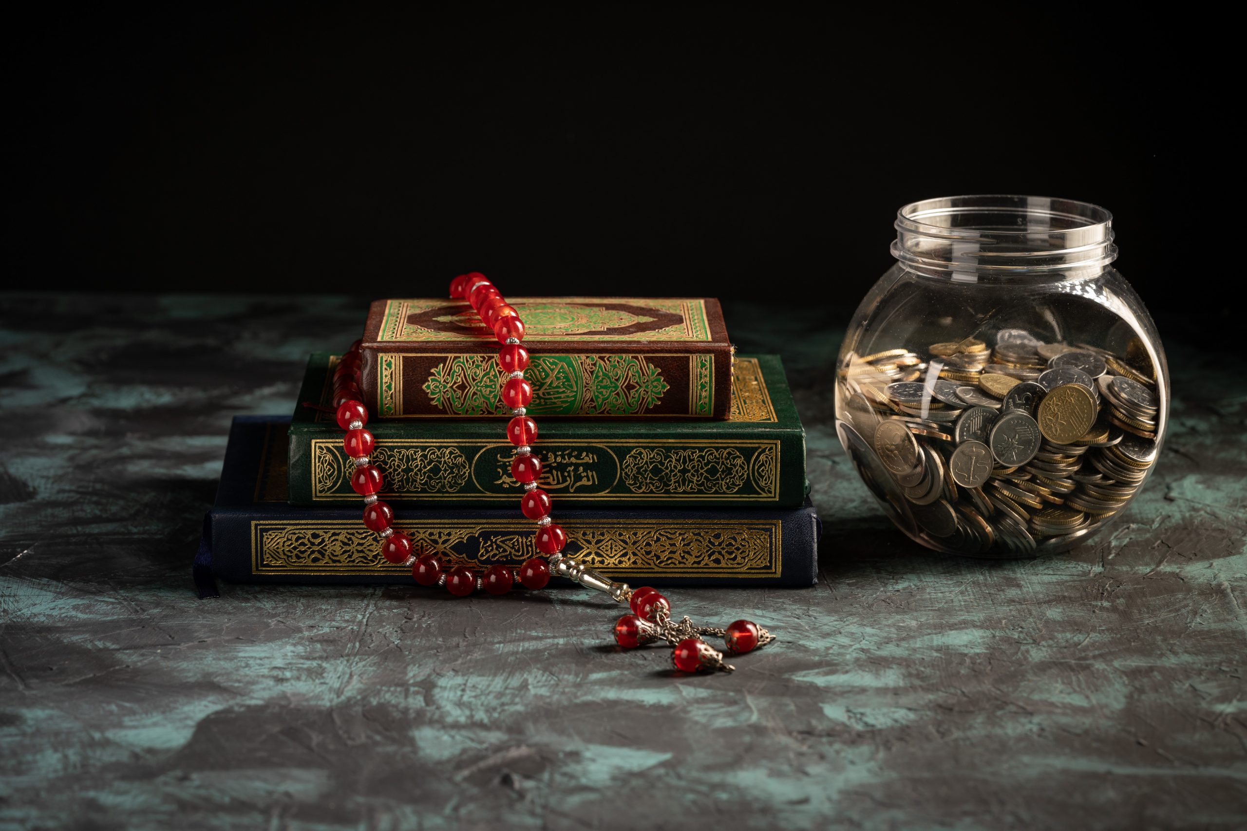 Zakat concept: Quran and tasbih with jar full of coins