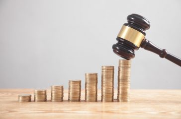 Stack of coins with judge gavel.