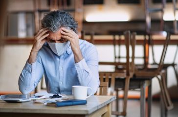 Frustrated owner sitting at table in closed cafe, small business lockdown due to coronavirus.