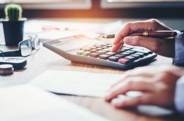Businessman's hands with calculator and cost at the office and Financial data analyzing counting on wood desk