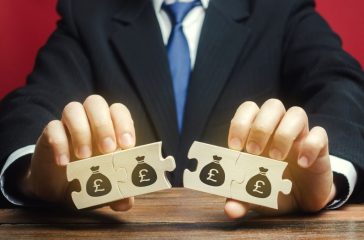 Businessman separates the wooden puzzle with a picture of money. The concept of financial management and distribution of funds. Saving and investing. Property division. Legal services.