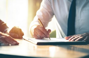 Closeup Businessman signing a contract investment professional document agreement on the table with pen.