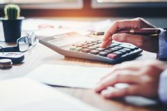 Businessman's hands with calculator and cost at the office and Financial data analyzing counting on wood desk