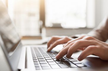 Typing on laptop closeup, chatting in Facebook