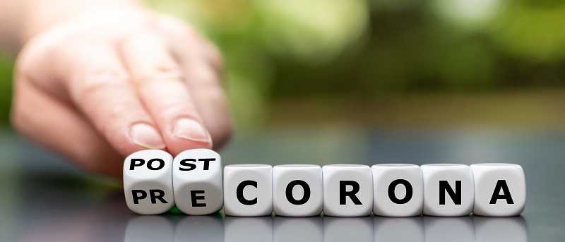 Hand turns dice and changes the expression "pre corona" to "post corona".