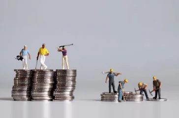Miniature people standing on a pile of coins. A concept of income disparity.