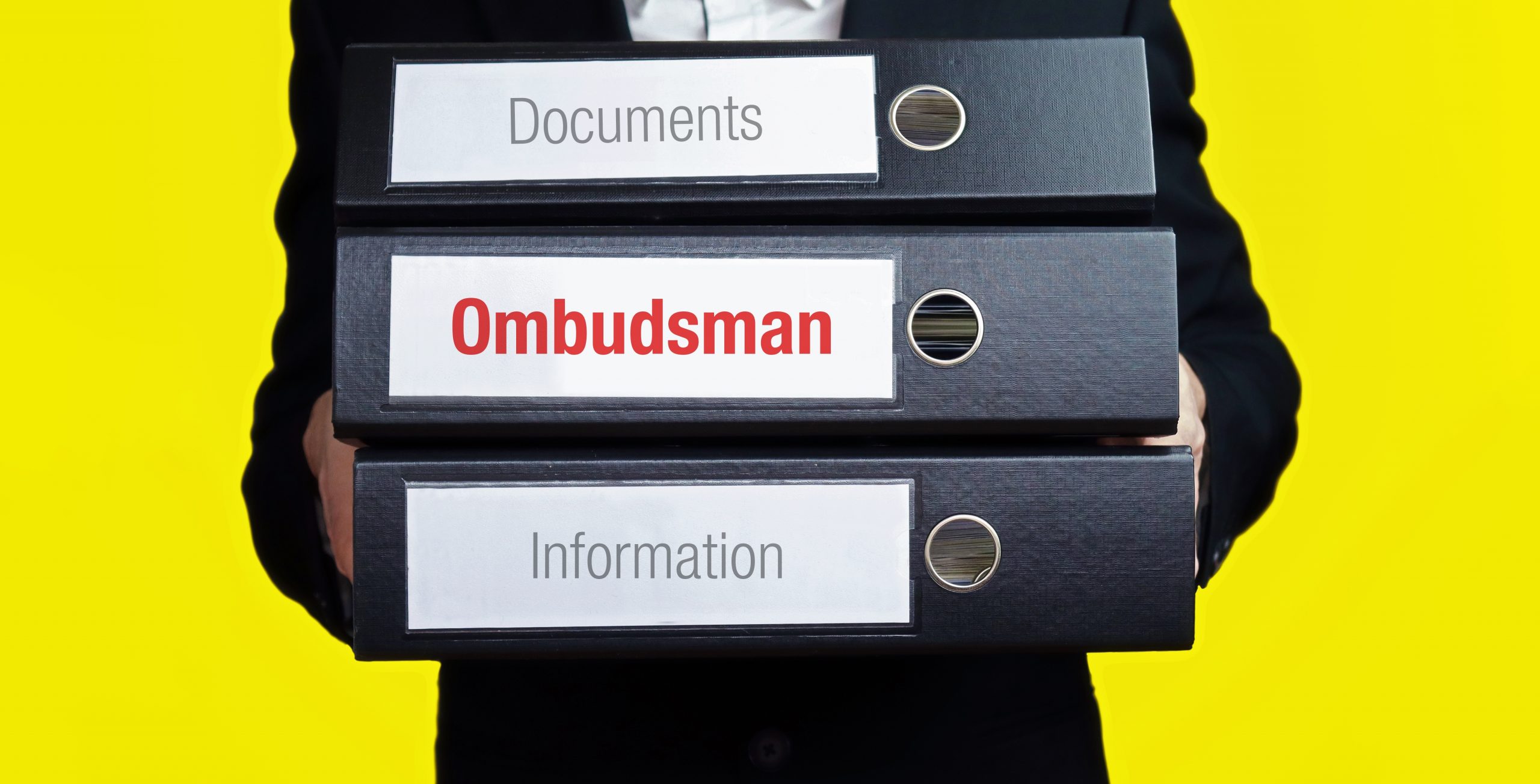 Ombudsman – finance/economics. Man carries a stack of 3 file folders. A folder has the label Ombudsman. Business, statistics concept