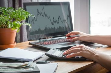 Investments. The girl buys stocks and analyzes the stock exchange, invests the budget in funds and stocks at home remotely. Work from home to quarantine, freelance. Work remotely.