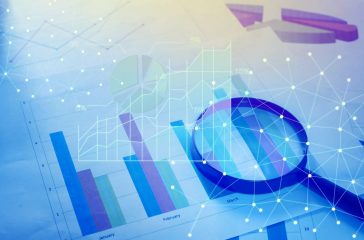 Magnifying glass and documents with analytics data lying on tabl