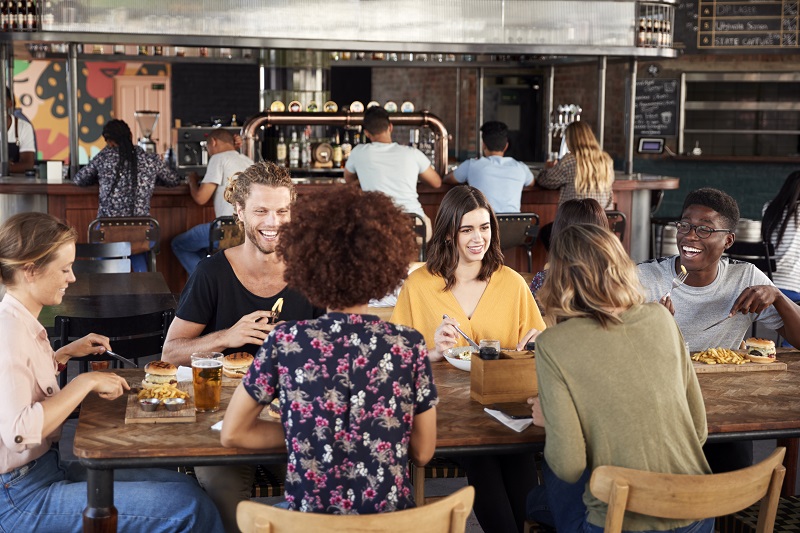 Group Of Young Friends Meeting For Drinks And Food In Restaurant
