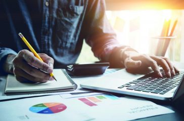 A man analysis business document with laptop computer counting w