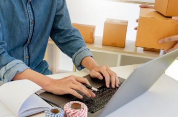 Startup small business entrepreneur SME, young asian man working with laptop computer and delivery packaging box, online market packing, SME e-commerce seller concept.