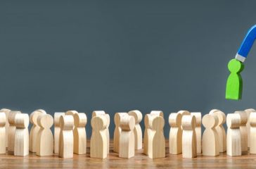 A hand with a magnet pulls green human figure out of the big crowd of people. Recruiting new workers, headhunters. Search for talented workers with great career potential. Selection. banner copy space