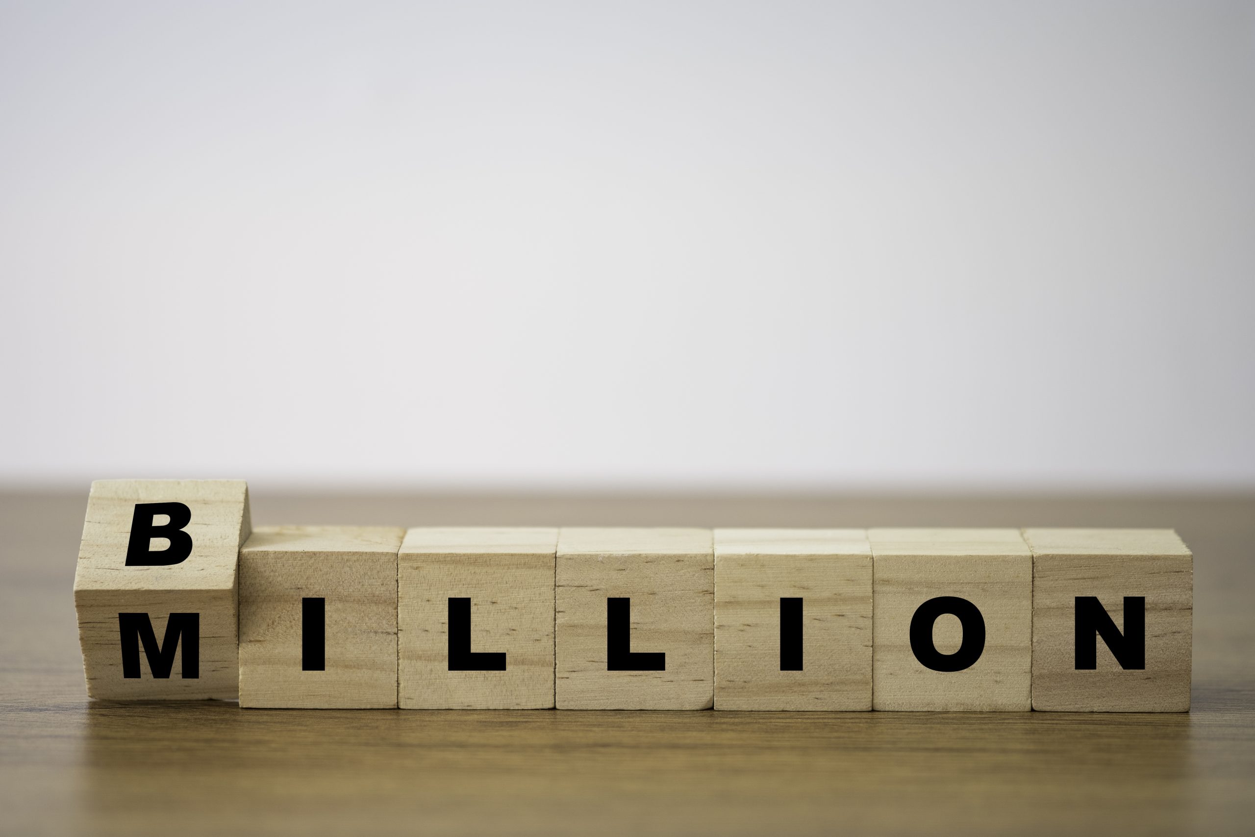 Flipping of wooden cube block for change million to billion. Business and investment growth concept.