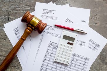 Bankruptcy concept. Judge hammer near financial documents on grey background top view