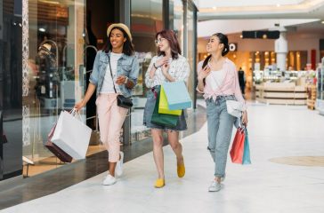 Stylish young smiling women walking with shopping bags, young gi