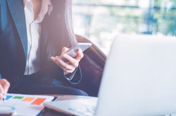 Business  woman uses a smartphone and writing on charts and grap