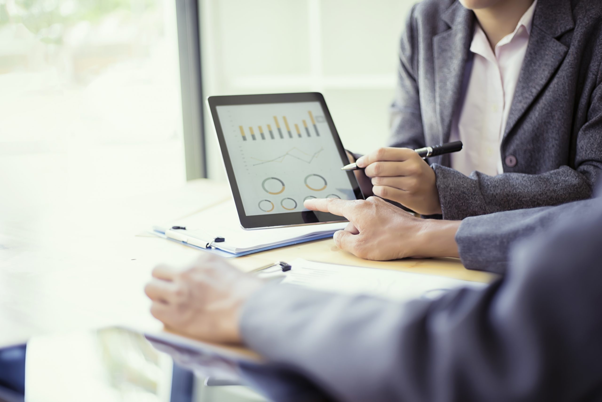 Business people analyzing investment charts with teblet in meeti