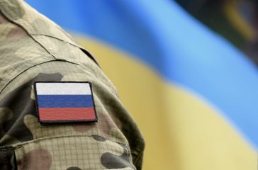 Flag of Russia on military uniform and flag of the Ukraine at ba