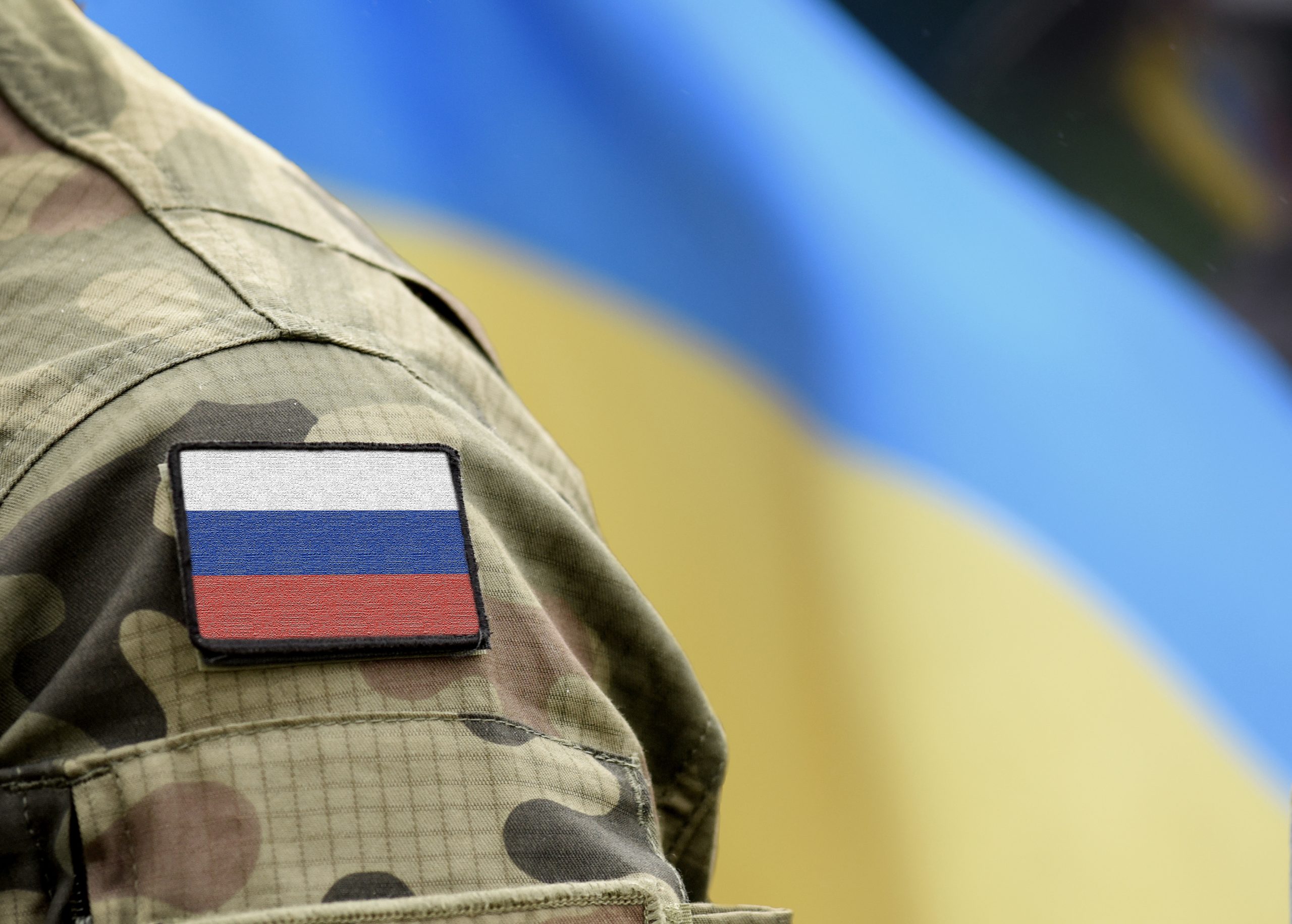 Flag of Russia on military uniform and flag of the Ukraine at ba
