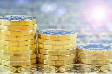 Golden coins in three descending stacks with lights effects.