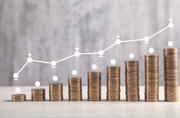 Coins on white table with profit graph.