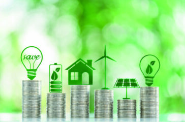 Renewable or clean energy generation prices and costs, financial concept : Green eco-friendly symbols atop coin stacks e.g. energy efficient light bulb, a battery, a solar cell panel, a wind turbine. Renewable or clean energy generation prices and costs, financial concept : Green eco-friendly symbols atop coin stacks e.g. energy efficient light bulb, a battery, a solar cell panel, a wind turbine.