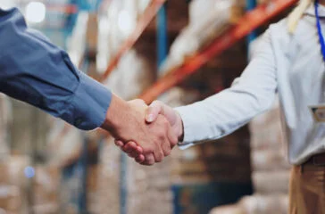 Handshake, agreement and teamwork for people in warehouse, meeting and deal for supply chain. Partnership, logistics and management shaking hands, distribution collaboration and courier company