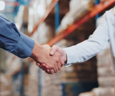 Handshake, agreement and teamwork for people in warehouse, meeting and deal for supply chain. Partnership, logistics and management shaking hands, distribution collaboration and courier company